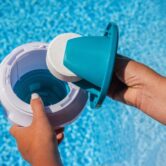 Hands,Placing,Chlorine,Tablet,Into,Pool,Dispenser,For,Water,Treatment
