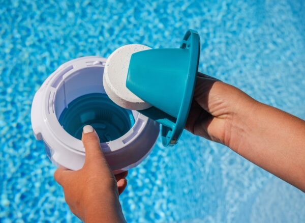 Hands,Placing,Chlorine,Tablet,Into,Pool,Dispenser,For,Water,Treatment