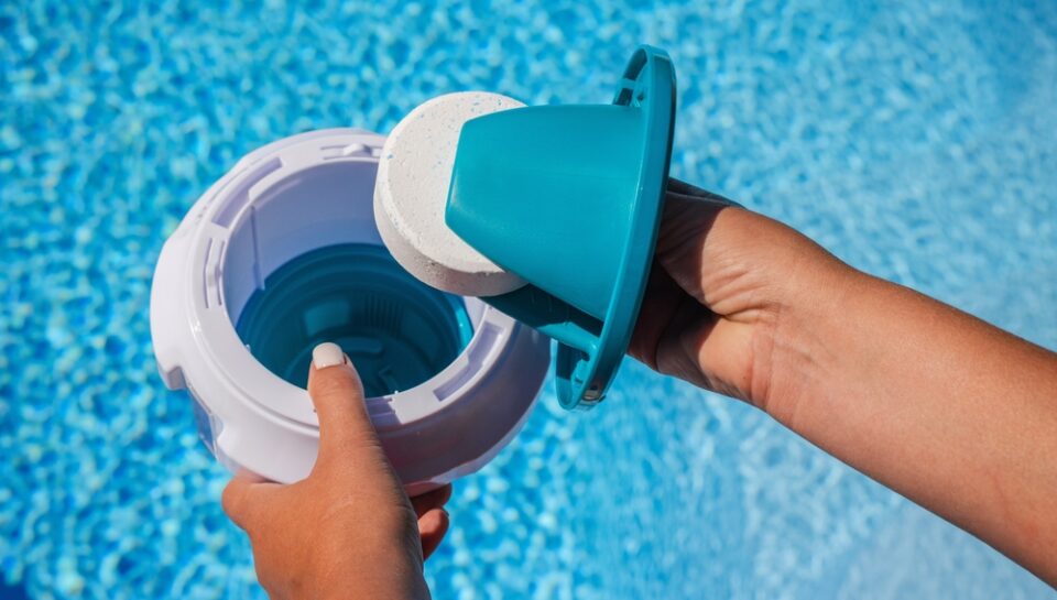 Hands,Placing,Chlorine,Tablet,Into,Pool,Dispenser,For,Water,Treatment